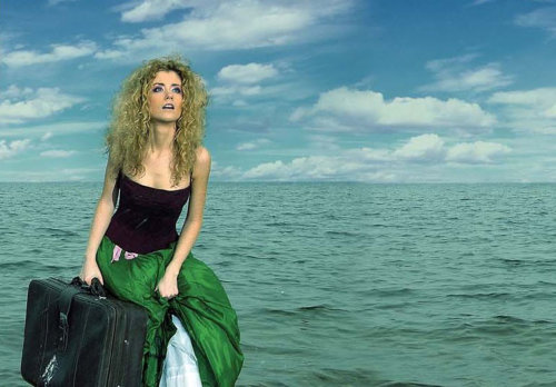 Frau mit Koffer am Meer